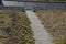 On the slope there are stairs in a row down. the staircase passes through a gabion wall to the asphalt pavement.