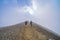 Slopes, light and shade on hillsides of mountains along Tongariro Alpine Walk with climbers ascending to summit of a peak