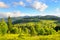 Slopes of mountains, coniferous trees and clouds in the sky.