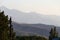 The slopes of the Trans-Ili Alatau mountains in the haze in autumn before sunset behind thickets of spruce and trees