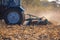 The sloping field. Big blue tractor plow plow the land after harvesting the maize crop on a autumn day.