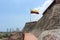 The sloping rock walls of the Castillo San Felipe de Barajas in Cartagena with the Colombian flag on a hot sunny day