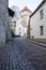 Sloping street of old town behind fortress wall with tower on background