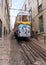 Slopped cobblestone street with cable car on rail tracks in the old town, in afternoon shadows, Lisbon, Portugal