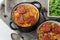 Slovak Christmas national cabbage soup in two small black pots with sausage on the tablecloth background