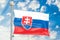 Slovak flag waving in blue cloudy sky, 3D rendering