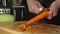 SLOW: Cook cleans a carrot on a cutting board