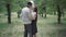 Slow dance of happy elegant young couple in summer park. Smiling loving man and woman dancing outdoors and talking