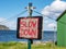 Slow Down - a sign saying `Slow Down` on a painted wooden board which is hanging from a pole that carries a washing line.