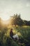 Slow living. Fashionable woman relaxing in summer countryside. Stylish elegant girl sitting on rustic chair in sunset light in