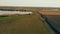 Slow low flying drone antenna over the lake , corn autumn field and dirt road in cloudy weather.