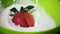 Slow mo. Strawberry falls into a bowl with yogurt