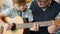 Slow motion of adorable child learning to play the guitar with grandad at home