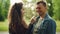 Slow motion of adorable couple having fun in the park, young woman is blowing dandelion blowball in her boyfriend`s face