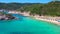 Slow motion aerial view along Mediterranian sea coast, green forest mountains, blue clear water, white sandy beach. Beautiful bay