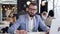 Slow motion of attractive young businessman with well-groomed beard and glasses sitting at his workplace and showing ok