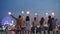 Slow motion of attractive young people holding burning sparklers standing on rooftop with their backs to the camera at