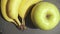 Slow motion bananas and an apple lie on a baking sheet