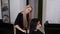 Slow motion of beautiful blonde hairdresser combing with hairbrush the female client`s wet straight hair, preparing and