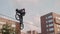 Slow motion of biker doing tailwhip trick on BMX bicycle. Building and blue sky on background