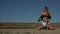 Slow motion blond woman sits on her knees in the desert