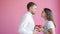 Slow motion of boyfriend giving gift box to pretty girl kissing on pink background