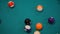 Slow motion: breaking racked pool balls on teal billiard table - close up