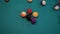 Slow motion: breaking racked pool balls on teal billiard table - close up