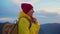 Slow motion camera follows woman hiker in yellow raincoat with backpack. Attractive happy young girl with backpack