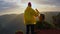 Slow motion camera follows woman hiker in yellow raincoat with backpack. Attractive happy young girl with backpack