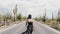 Slow motion camera follows young happy tourist woman lost walking along hot desert road in Saguaro cactus national park.