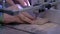 Slow motion: carpenter using bandsaw tool, cutting piece of wood - close up