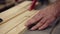 Slow motion carpenter wrinkled hands cutting wooden board on saw machine. Industrial machine with circular saw cuts