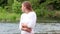 Slow Motion Caucasian Woman Blond Half-Length Standing With River In Background