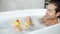 Slow motion of cheerful young man playing with toy ducks in bathtub alone