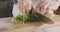 Slow motion of chef knife slicing celery leaves