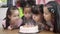 Slow motion - Children celebrate birthday`s party in classroom, Multi-ethnic young girls happy make a wish blow out candles on