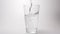 SLOW MOTION: Clear water pour into a transparent glass on a white background