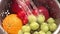 Slow motion close up of fruit being washed by water in a colander.