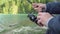 Slow motion close up of a man holding a fishing rod and reel or angler on a sunny day near lake.