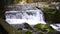 SLOW MOTION, CLOSE UP: Powerful raging whitewater waterfall falling forcefully over a rocky edge. Crystal clear glacier