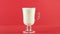 Slow motion close-up shot of cold diary milk cold beverage drink pooring into latte glass mug red background in studio