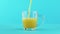 Slow motion close-up shot of fruit orange multifruit juice cold beverage drink pooring into glass mug with rounded
