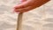 Slow motion, close up: unknown playful young woman throws a handful of white sand. Time is running like the sand through