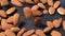 Slow motion close up of unpeeled almonds falling into dark grey cast iron pan for roasting spices