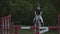 Slow motion, close up: young horsegirl horseback riding strong brown horse jumping the fence in sunny outdoors sandy