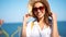 Slow motion closeup attractive happy girl tourist straw hat and eyewear posing at seaside at sunny day