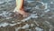 Slow motion closeup barefoot female legs on beach with rolling waves.