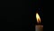 Slow motion closeup burning single candle flame isolated on black background