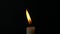 Slow motion closeup burning single candle flame isolated on black background